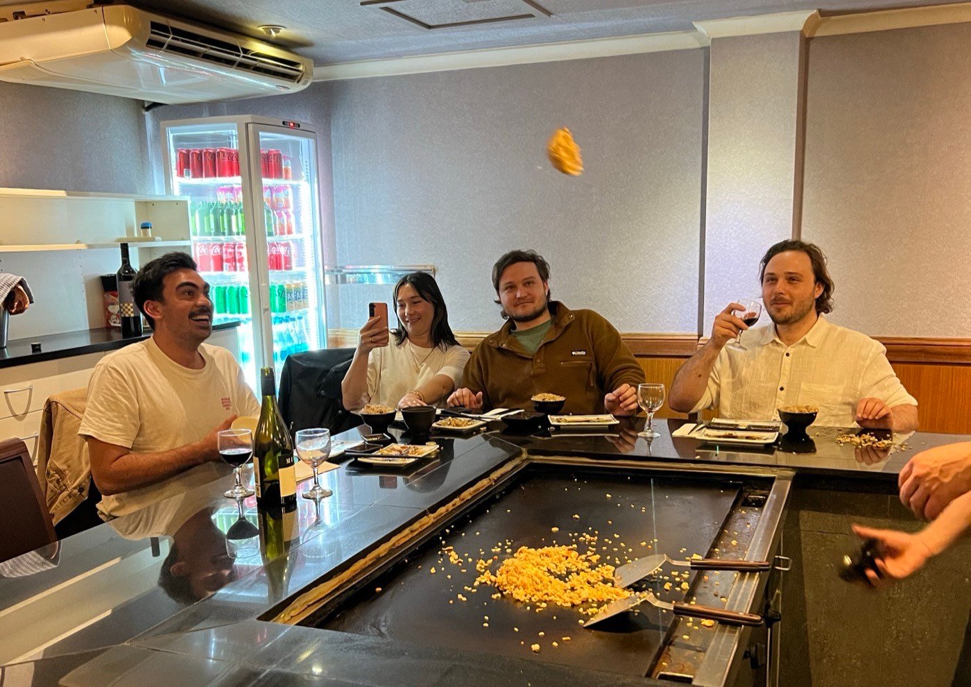 A ball of fried rice in mid-air above the teppanyaki hotplate at Fujiya, while four guests at the counter watch, laugh and film it